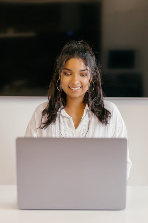 Gratis Estudiante Femenina Sonriendo Mientras Usa Una Computadora Portátil Foto de stock