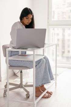 Woman studying indoors with a laptop in a modern, bright space.