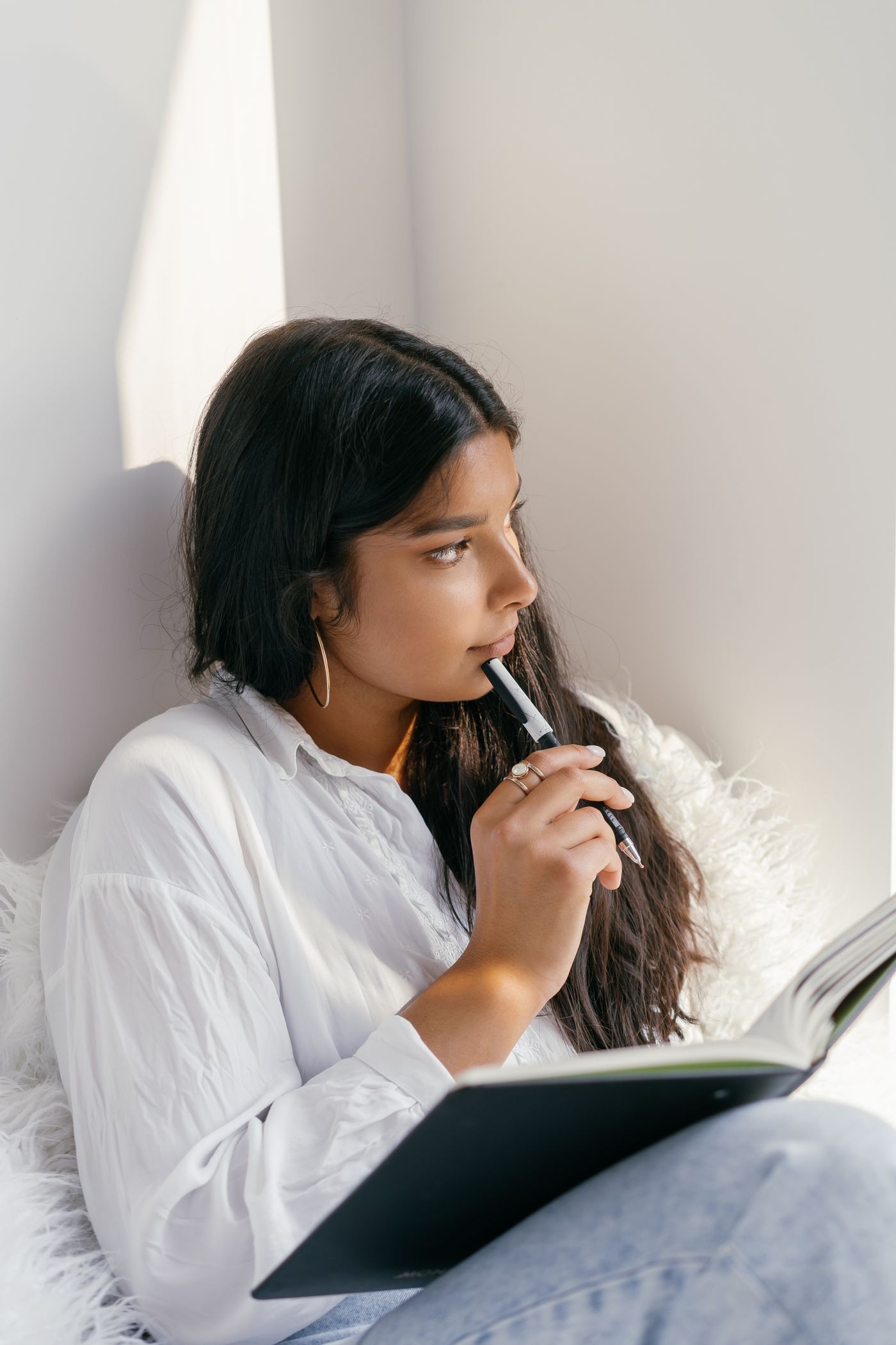 Woman pondering with a pen in a bright room