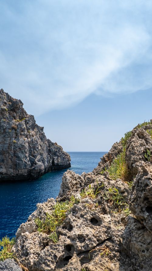 Free Vivid view of rocky cliffs and azure sea at Kalipso, Greece under a clear sky. Stock Photo