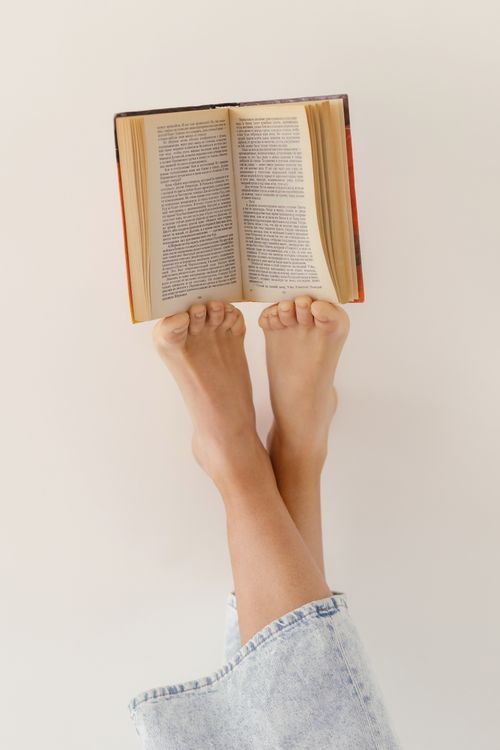 Free Woman relaxing with a book on her feet, enjoying leisure time indoors. Stock Photo