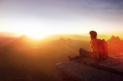 Free Man Sitting on Edge Facing Sunset Stock Photo