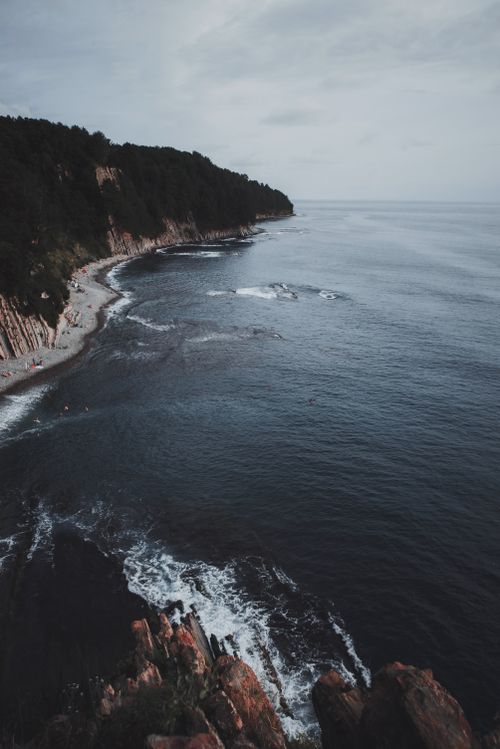 Free Aerial view of a dramatic coastal cliff and ocean waves at dusk. Stock Photo