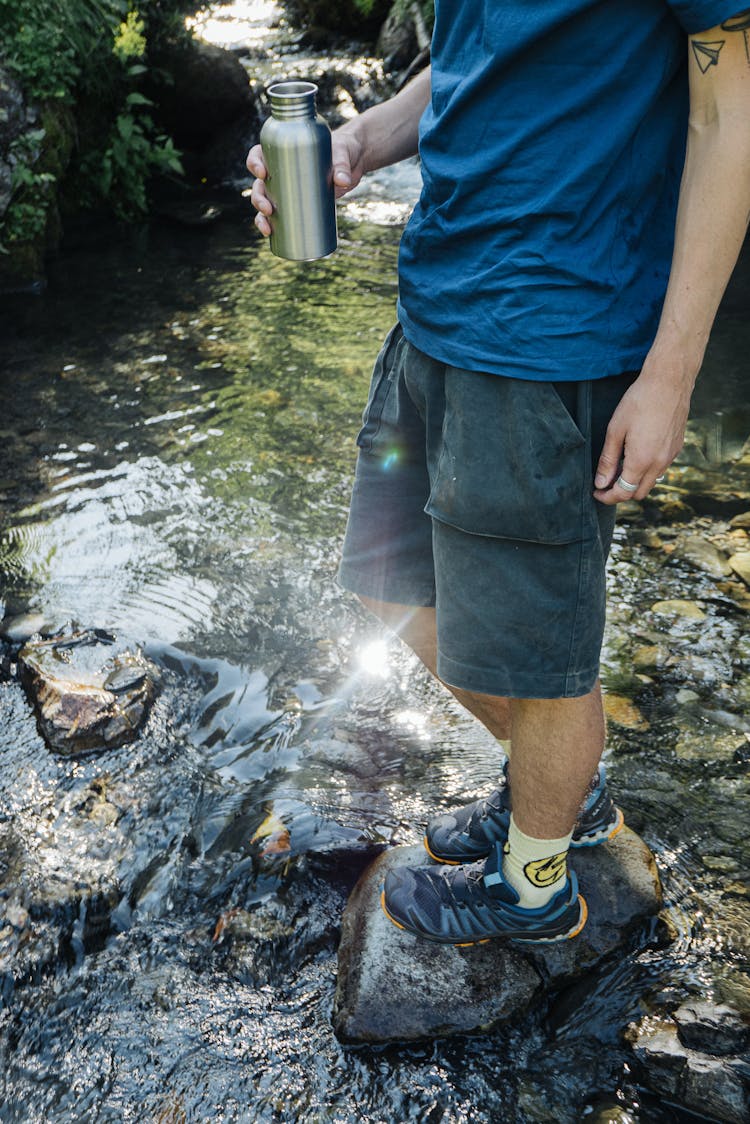 Man Holding A Water Bottle While Standing On A Rock 