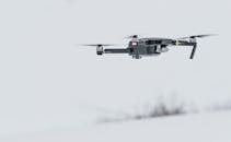 一架现代无人机飞越宁静的雪原，展现了先进的技术