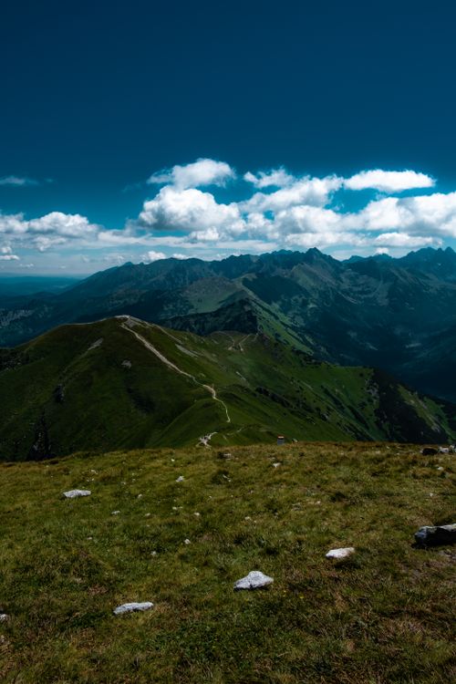 Free Stunning view of green mountains under a clear blue sky with scattered clouds, perfect for nature photography. Stock Photo