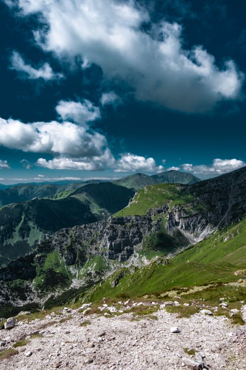 Free A stunning view of lush green mountains under a vivid blue sky with fluffy clouds. Stock Photo