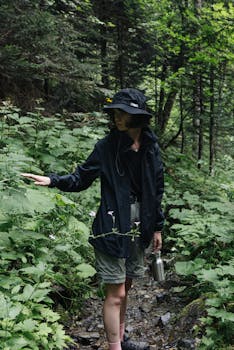 A woman in a black bucket hat explores a lush green forest trail during summer.