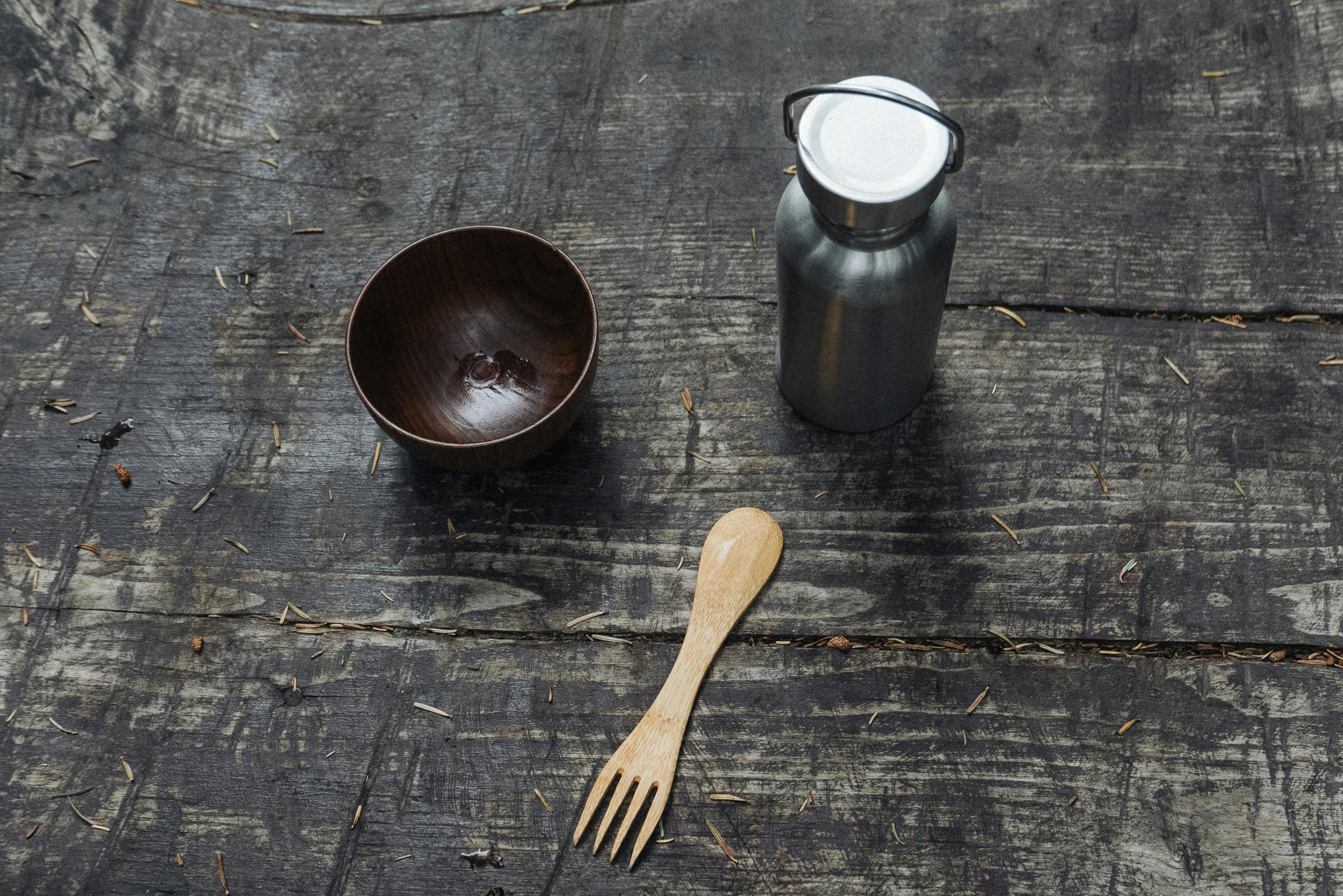 a wooden bowl and fork near the stainless tumbler