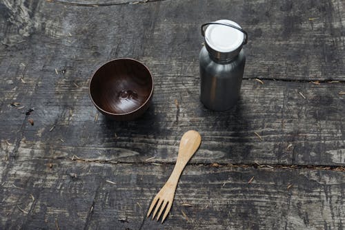 A Wooden Bowl and Fork Near the Stainless Tumbler