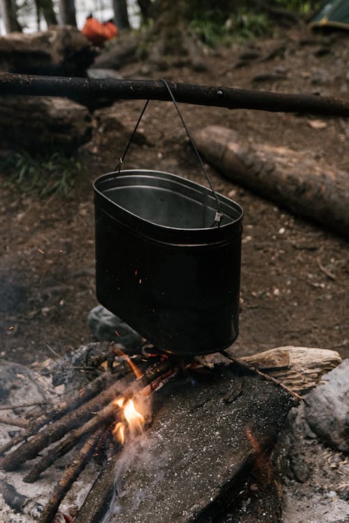 Tin Container Hanging on a Stick above a Fire 