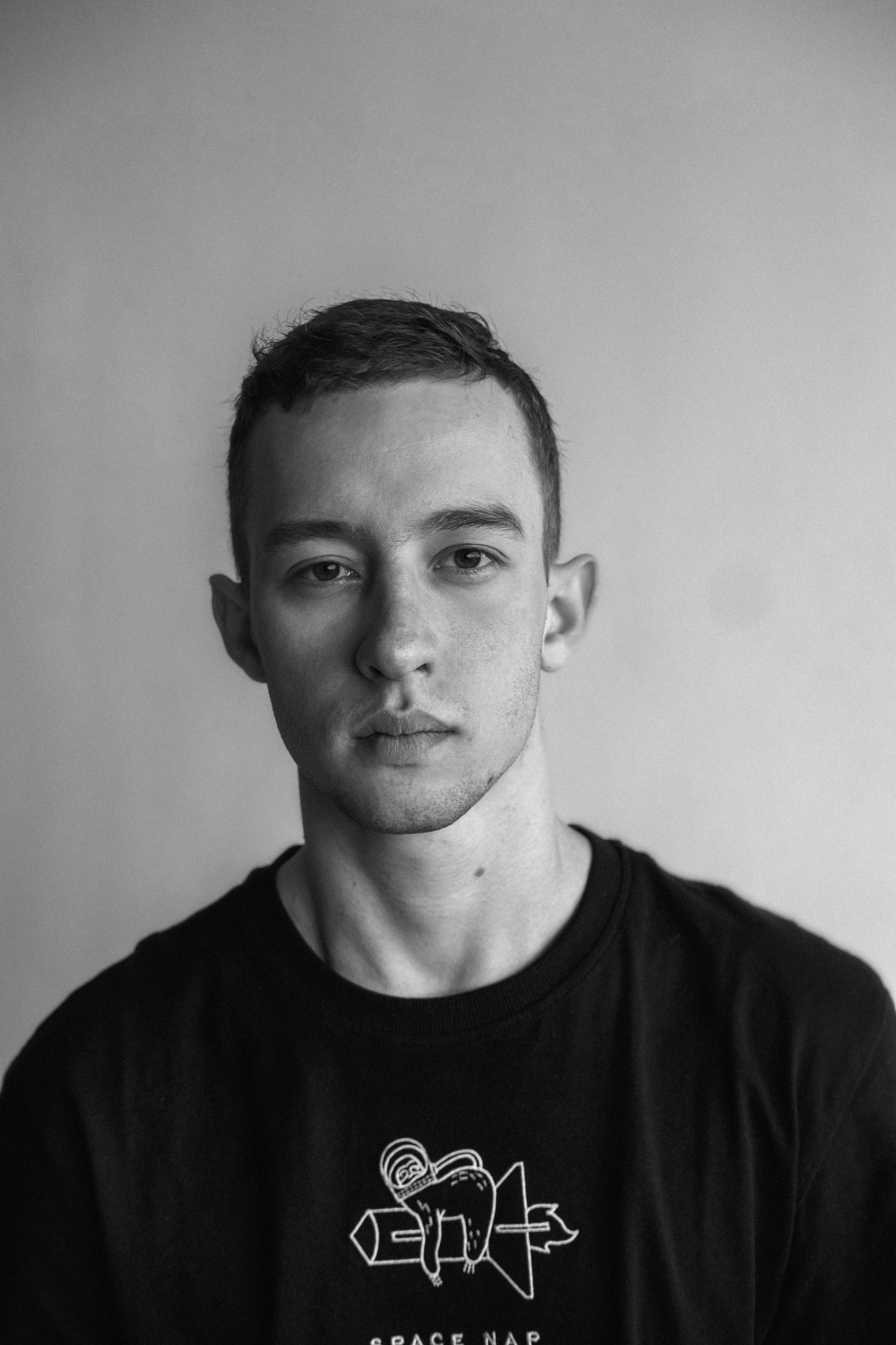 Striking black and white portrait of a young man with neutral expression.