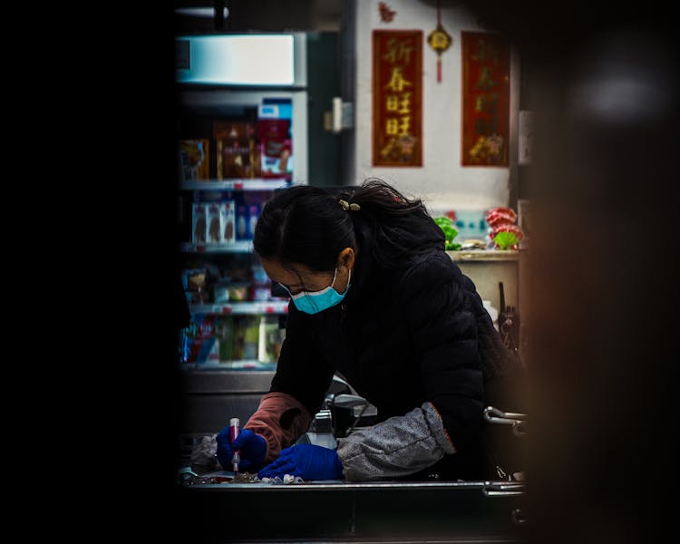 Woman In Mask Working On Table At Store