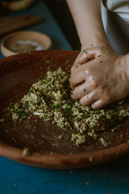 Free Close-up of hands mixing herbs and ingredients in a wooden bowl, showcasing traditional food preparation. Stock Photo