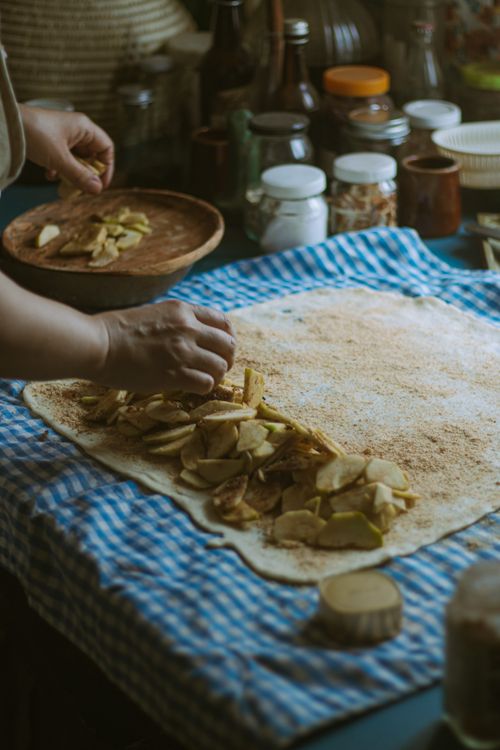 Free Woman preparing apple filling on dough for baking in cozy home kitchen setting. Stock Photo
