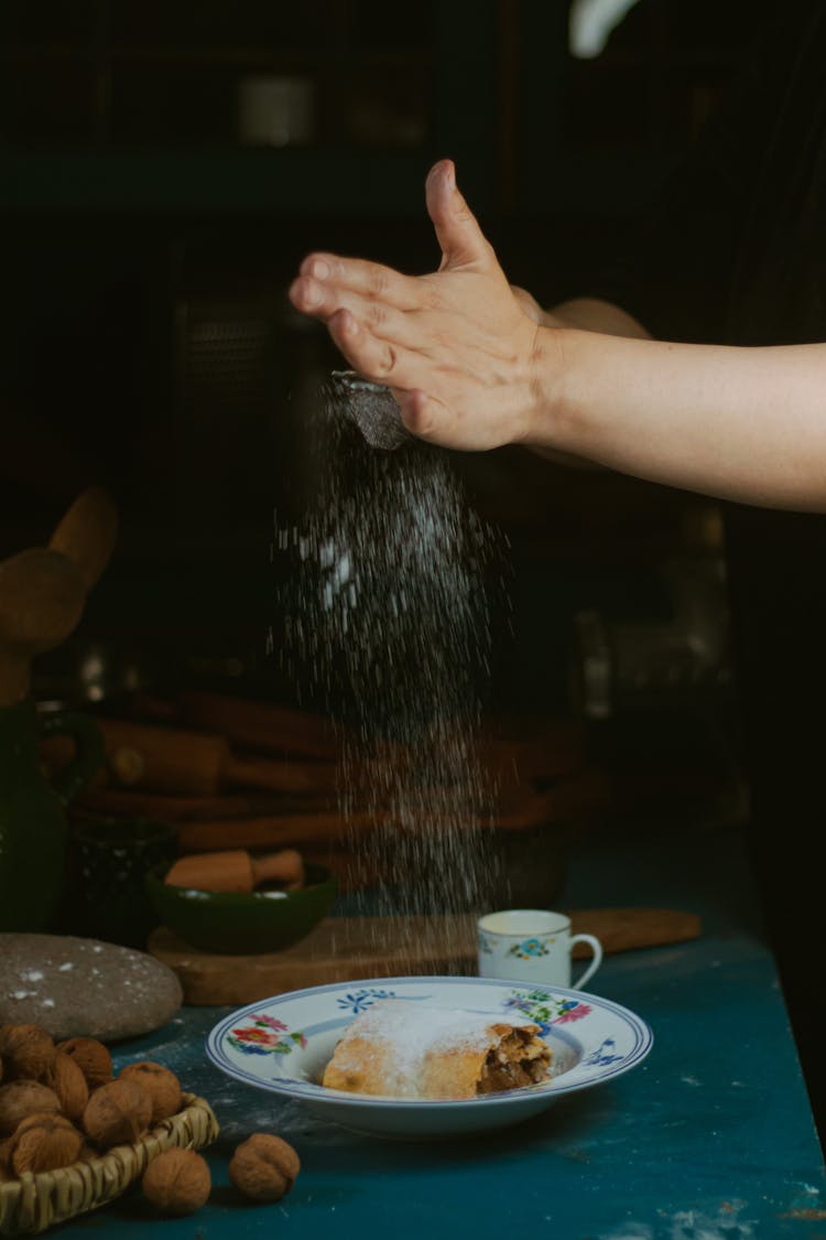 Hand Sprinkling Powdered Sugar On Pastry