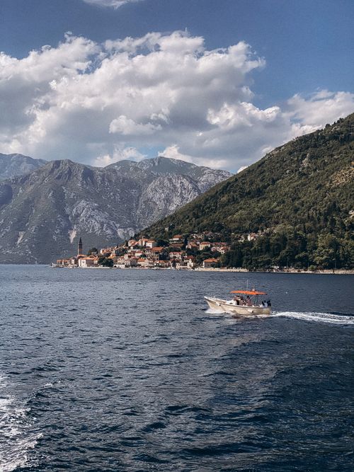 Free Small boat sailing near a picturesque coastal village surrounded by mountains and sea. Stock Photo