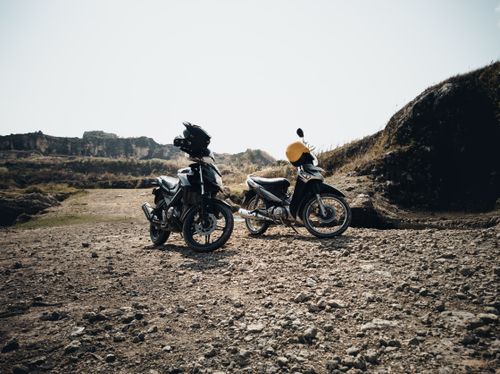Free Two motorbikes parked on a rough, rocky terrain under a clear sky, ideal for off-road adventures. Stock Photo