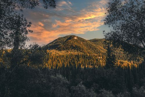 Free Scenic view of a lush green mountain landscape under a vibrant sunset sky. Stock Photo