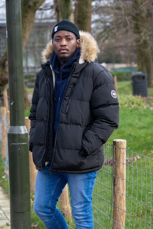 Man in Black Puffer Jacket Standing Near Fence