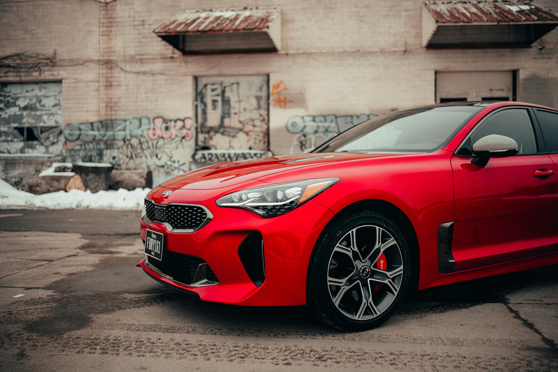 Red luxury car parked against a graffiti-covered wall in Des Moines. Urban and modern vibe.