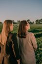 2 Women in Brown Long Sleeve Shirt Standing on Green Grass Field