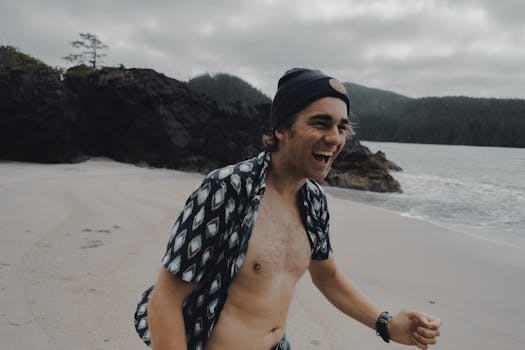 Cheerful man wearing a beanie enjoying a day at Tofino's scenic beach in British Columbia.