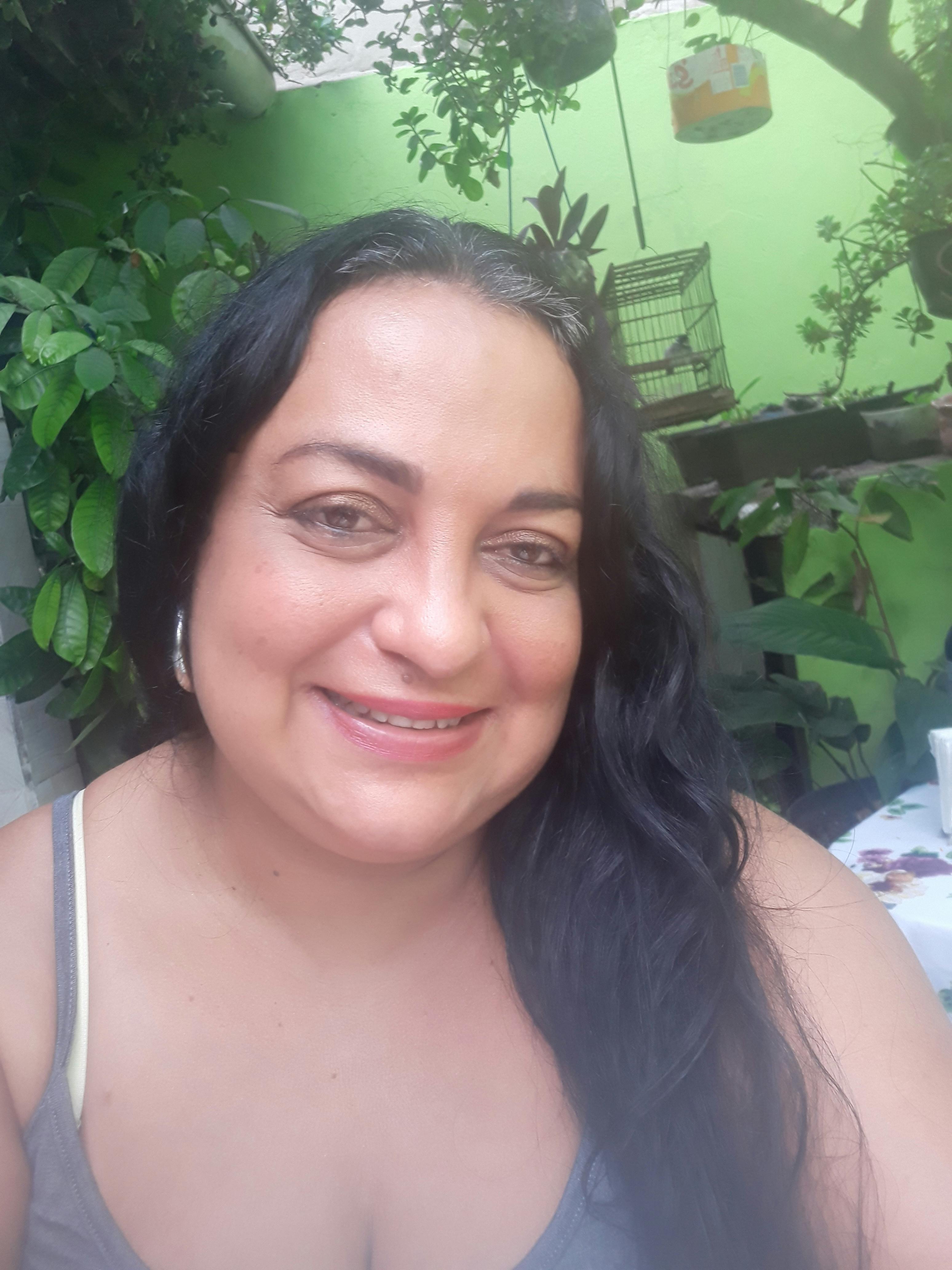 Person looking at a smartphone at a desk with a laptop, coffee, and notepad, suggesting checking online horoscopes