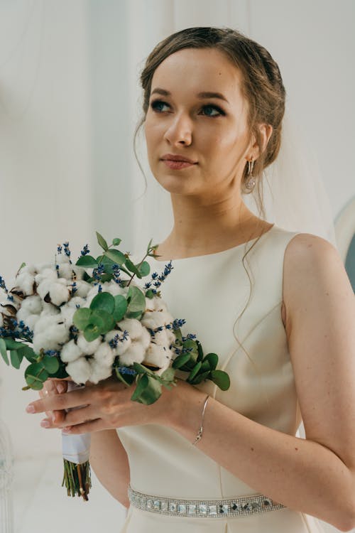 花の花束を保持している白いガウンを着ている女性