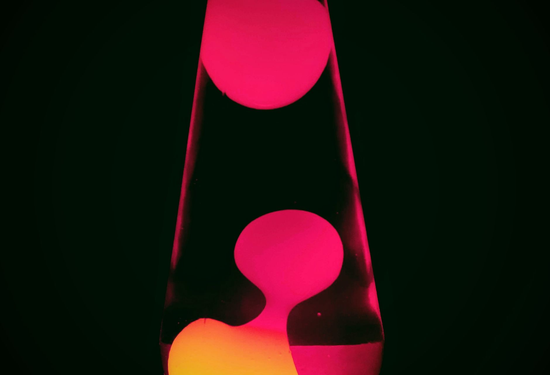 A vibrant pink lava lamp depicted in the dark, highlighting its flowing shapes.