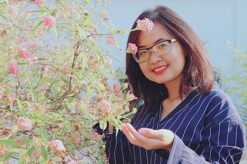 Woman in Blue Striped Top Holding Pink Flowers