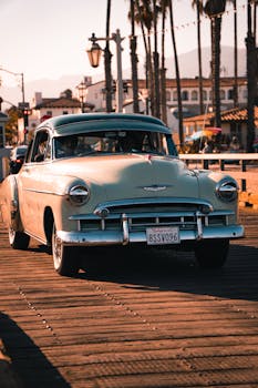 Classic vintage car parked on a wooden pier in Santa Barbara during sunset.