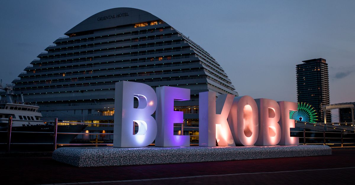 Evening scene of Kobe Harbor featuring the iconic 'Be Kobe' sign with Oriental Hotel in the background.
