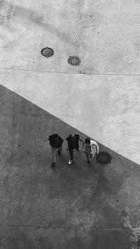 Black and white photo capturing three people walking on a street in Vladivostok, Russia.