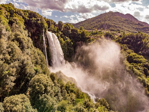 Waterfall in Hills Covered with Green Trees