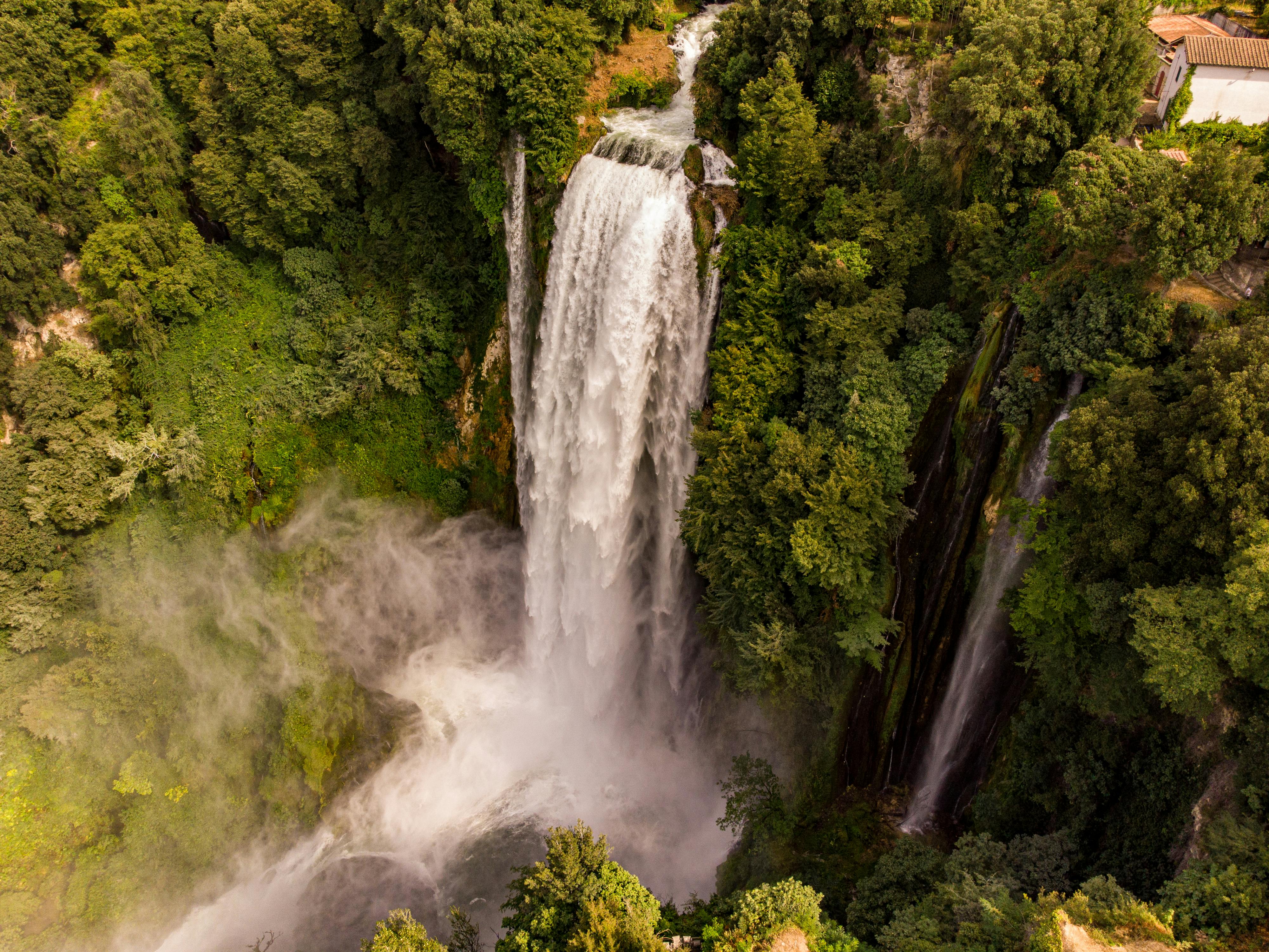 A breathtaking aerial view of a cascading waterfall amidst dense forest foliage, showcasing nature