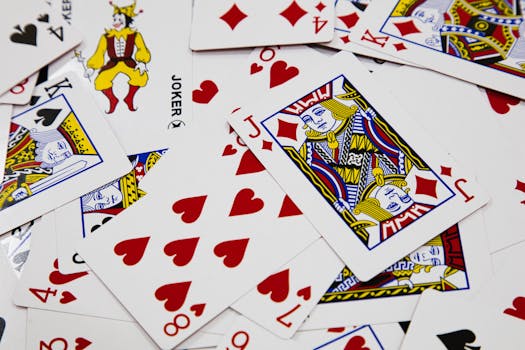 A vibrant arrangement of playing cards depicting various suits and a joker in a dynamic composition.