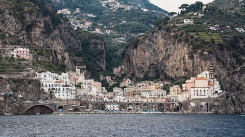 White Buildings Beside Mountain and Body of Water