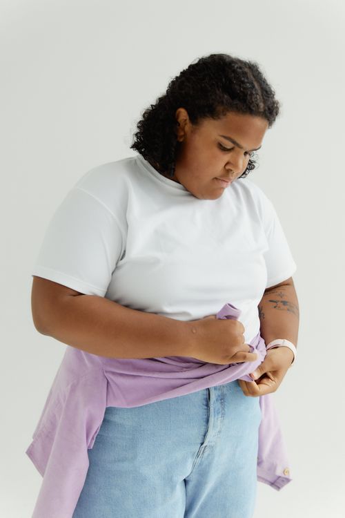 Free African American woman adjusting a purple jacket in a studio setting. Stock Photo