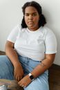 Woman in White Crew Neck T-shirt and Blue Denim Jeans Sitting on Brown Wooden Chair