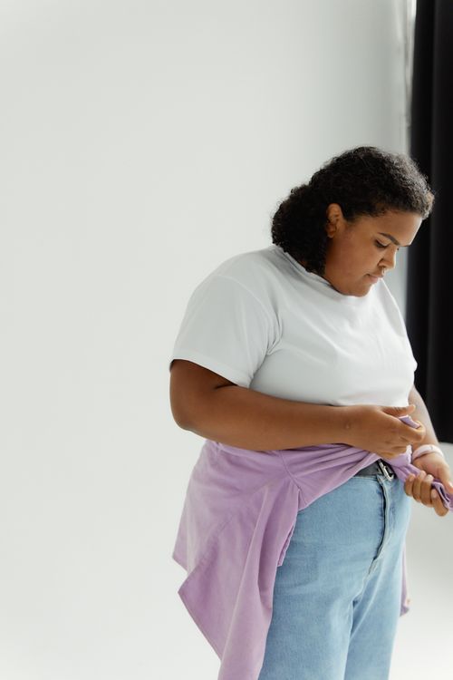Free Portrait of a young woman embracing body positivity in a casual studio setting with a white background. Stock Photo