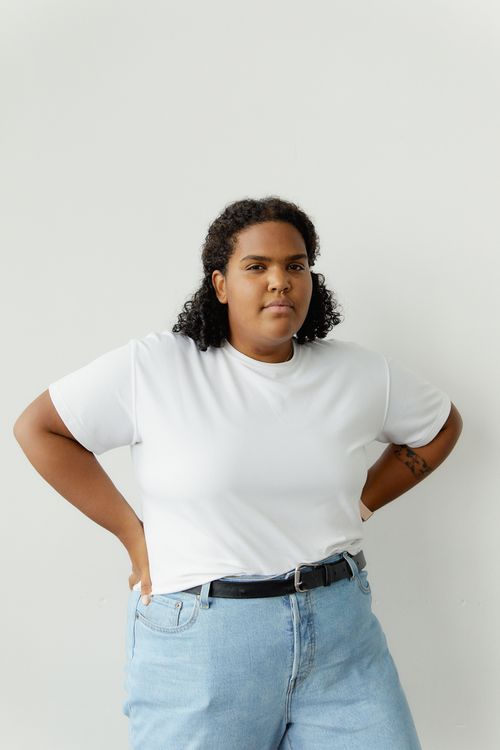 Free Portrait of a confident plus size woman wearing a white shirt and blue jeans against a white background. Stock Photo
