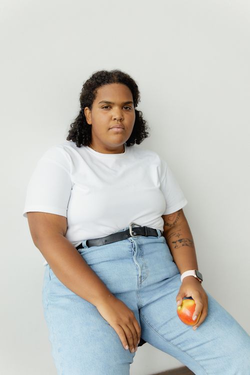 Free Portrait of a confident plus size woman in casual wear holding an apple. Body positivity concept. Stock Photo