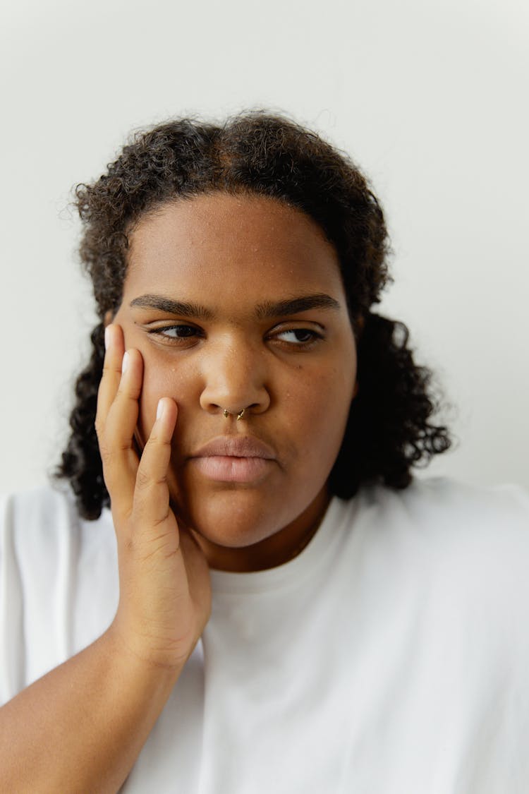 A Woman In White Crew Neck Shirt Touching Her Cheek