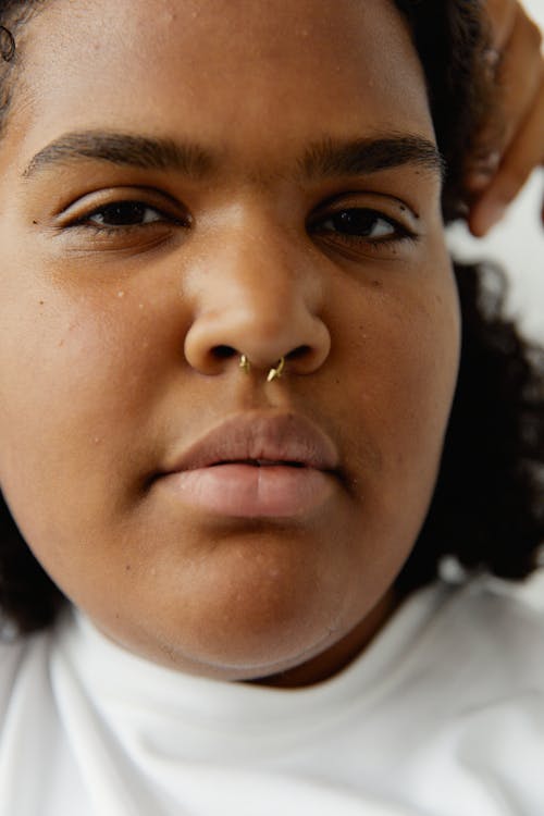 Free A Close-up  Shot of a Woman in White Crew Neck Shirt with Nose Piercing Stock Photo