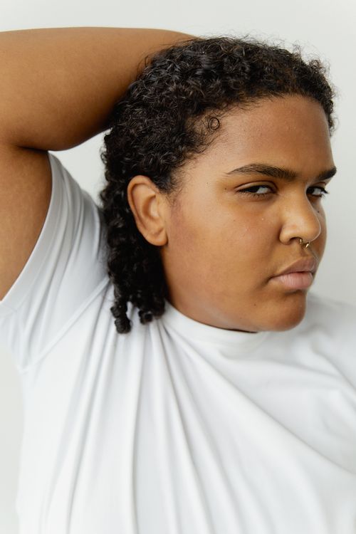 Free Portrait of a confident woman in a white shirt posing indoors with a thoughtful expression. Stock Photo