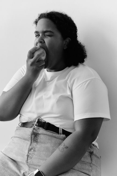 Free Black and white portrait of a woman taking a bite of an apple, capturing a joyful moment of snacking. Stock Photo