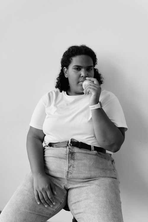 Free Black and white portrait of a woman sitting and holding a fruit, deep in thought. Stock Photo