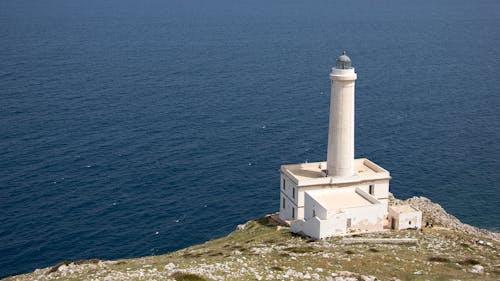 White Lighthouse on Cliff Near Body of Water
