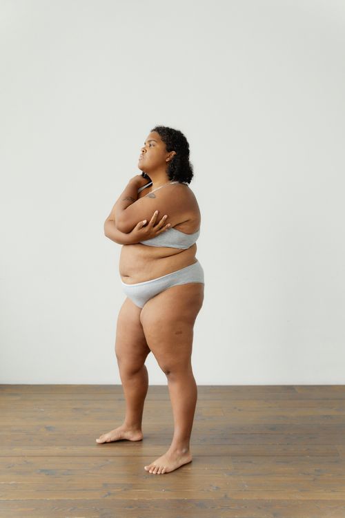 Free Empowering image of a plus size woman embracing her body in a studio setting. Stock Photo
